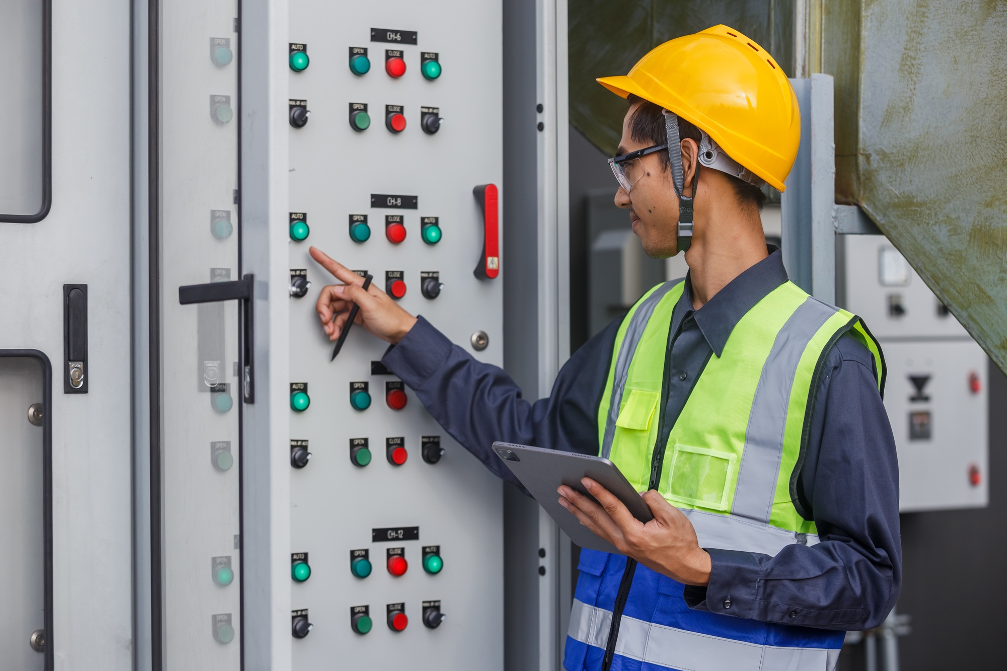Electrical engineer man using tablet checks switchboard main Distribution Boards control panel